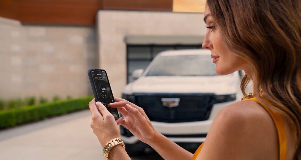 lady checking her mobile with a Cadillac vehicle background | Stevens Creek Cadillac in Santa Clara CA